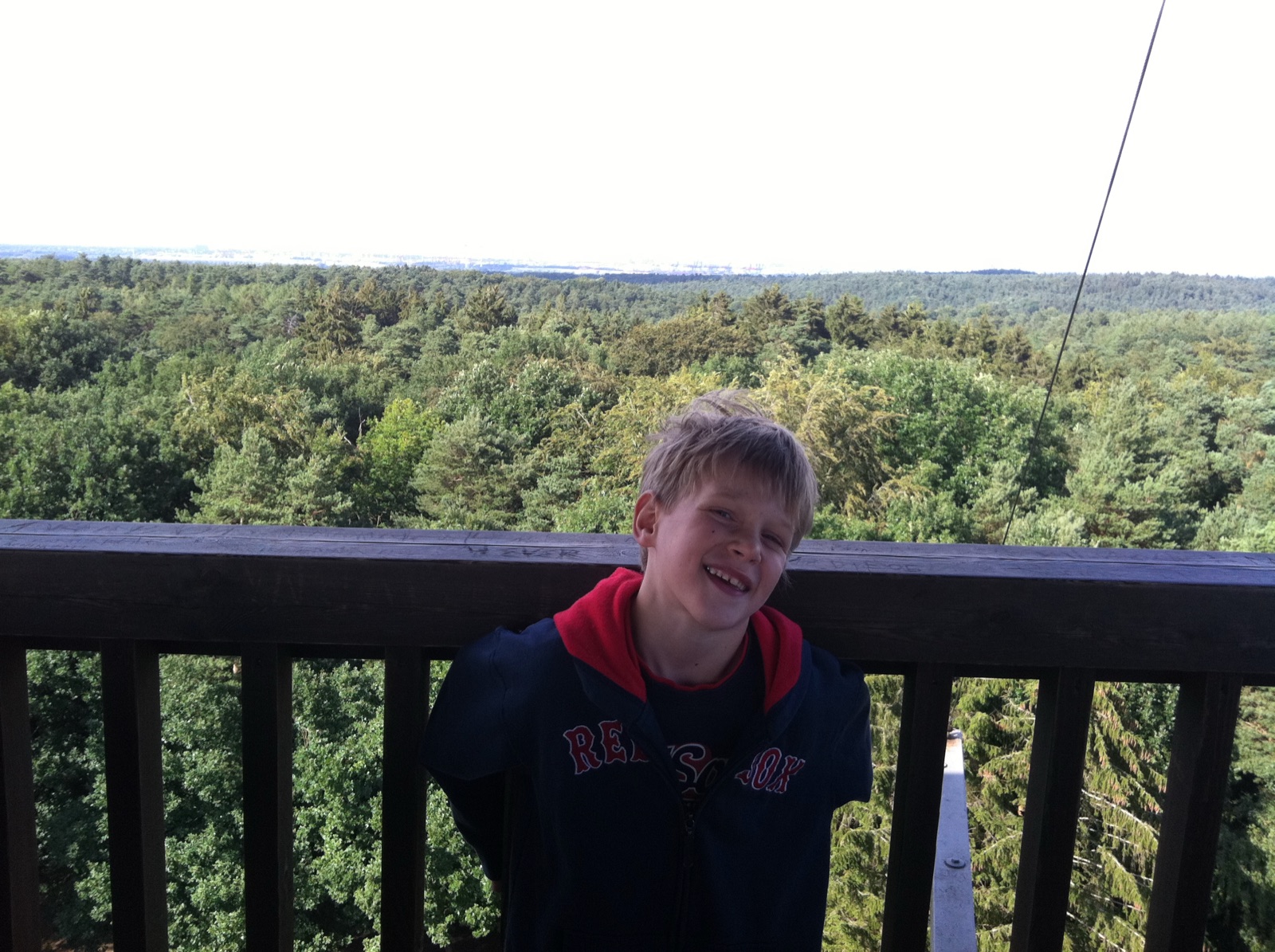 Jeremy as a child, grinning at the rail of a lookout tower above a forest